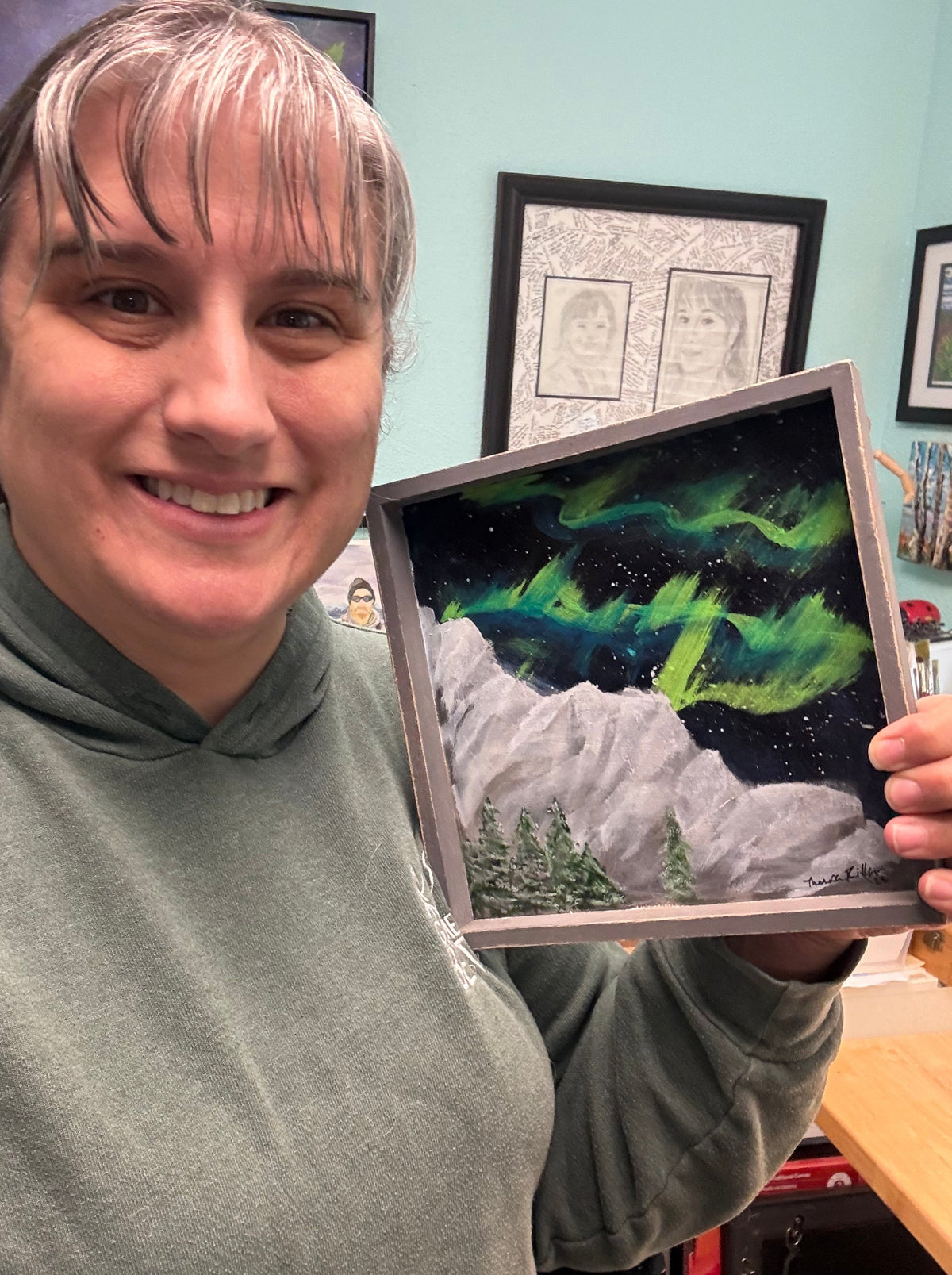 Wood panel painting of northern lights over mountains