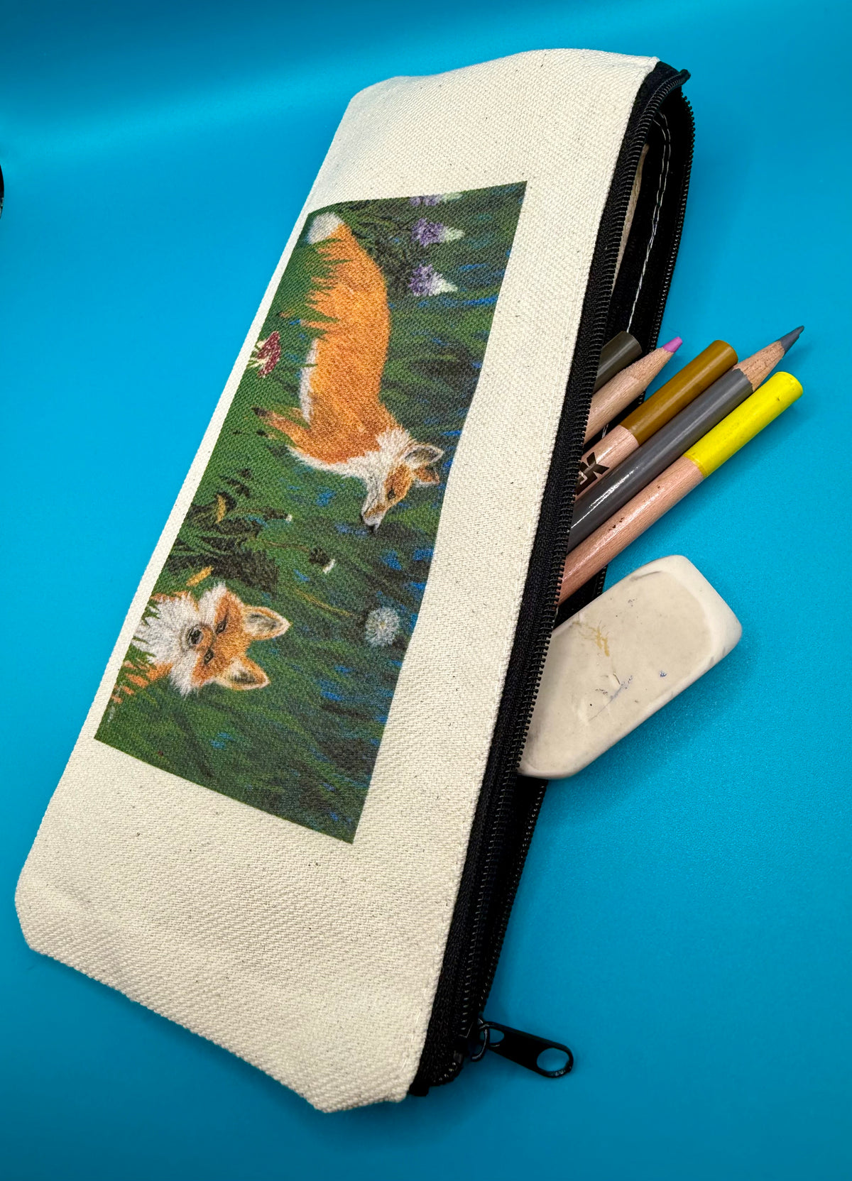 Pencil pouch with zipper pictured with examples of what it can hold.