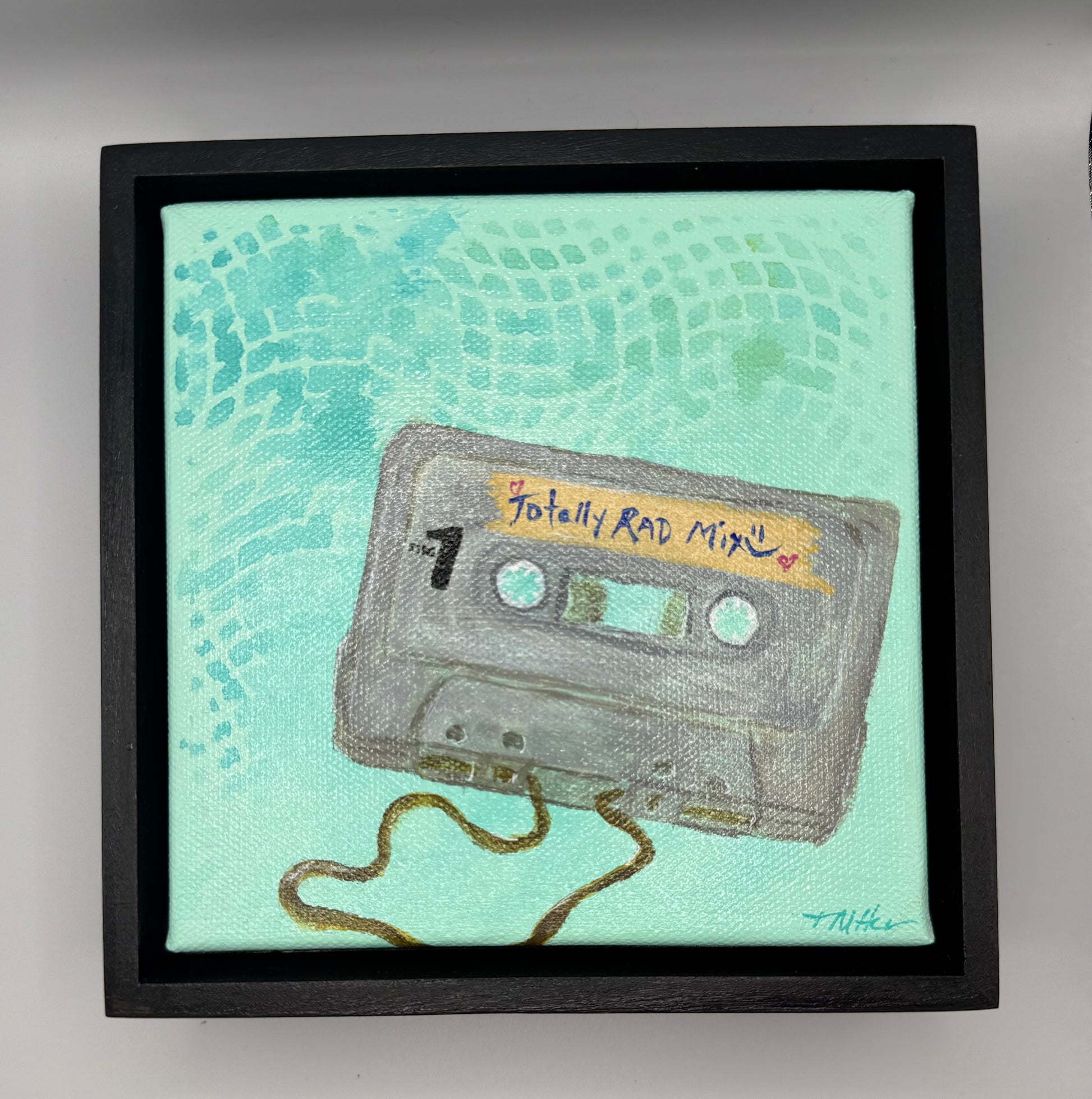 Image of acrylic painting with stenciled background and image of a mixed cassette tape that is framed in wood frame.