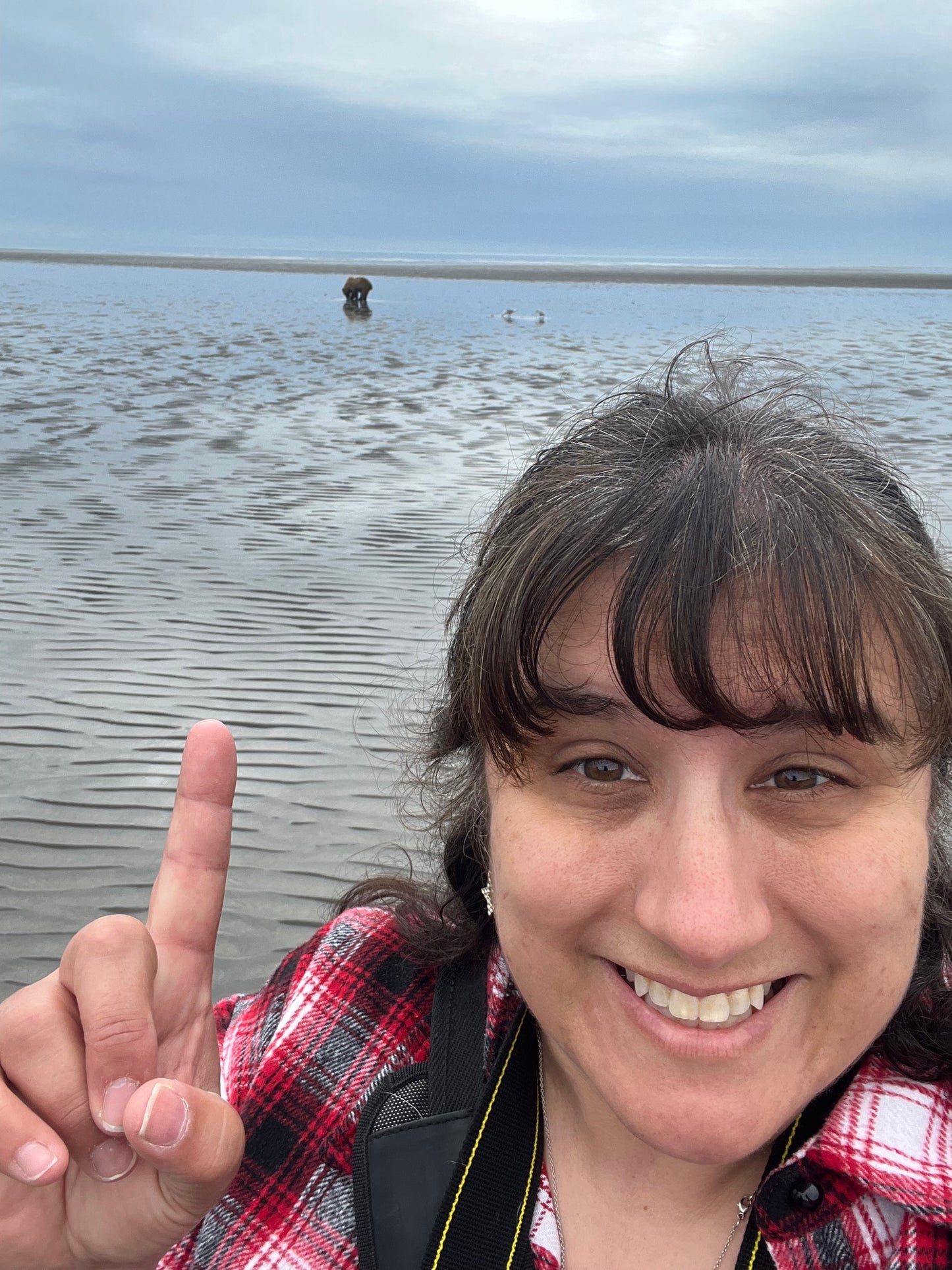 Artist Theresa Ritter on beach pointing to brown bear searching for clams. Inspiration for painting